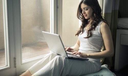 窓際でノートパソコンに向かう若い女性