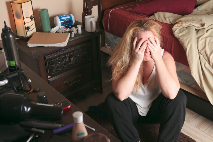 散らかった部屋で落ち込む女性