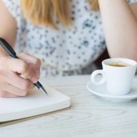 カフェで何か書いている女性