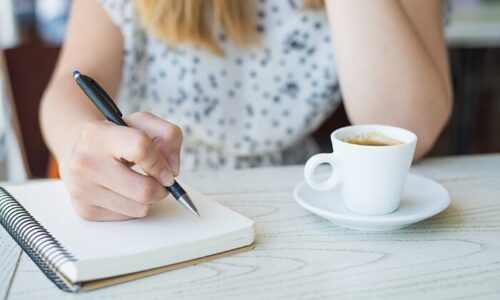 カフェで何か書いている女性