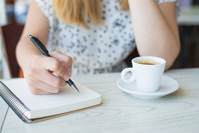 カフェで何か書いている女性