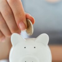 貯金箱にコインを入れる手