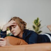 スマホを見ながらストレスを感じている女性