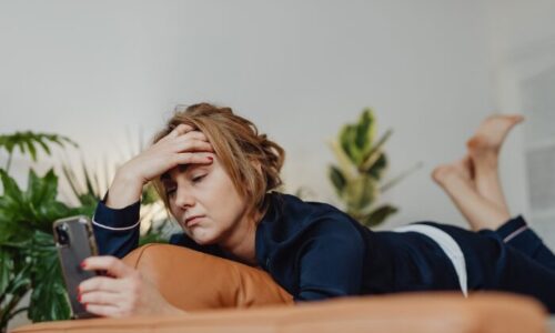 スマホを見ながらストレスを感じている女性