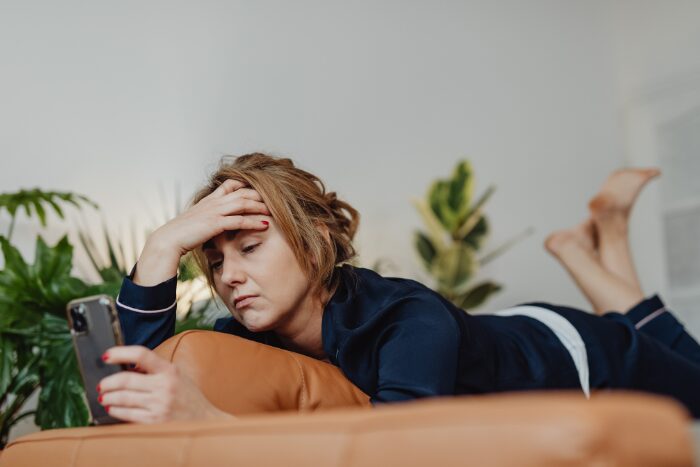 スマホを見ながらストレスを感じている女性