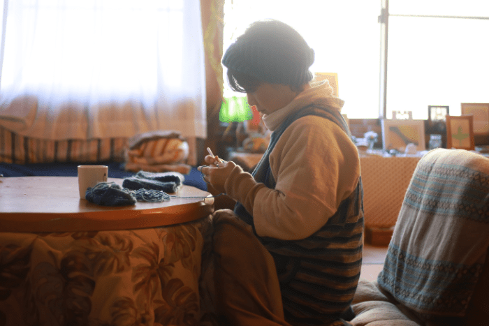 こたつで編み物をしている女性