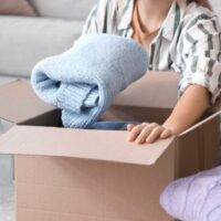 ダンボールにセーターを入れている女性