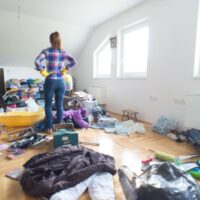 散らかった部屋に立つ女性