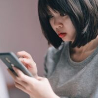スマホでカードの明細を見て驚いている女性