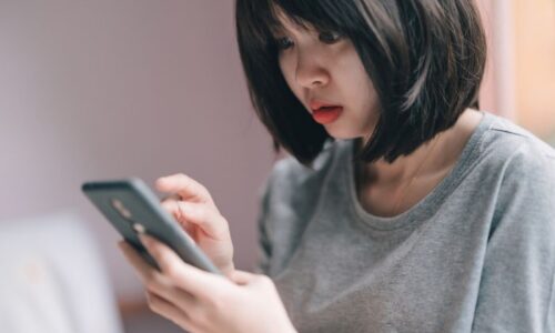 スマホでカードの明細を見て驚いている女性
