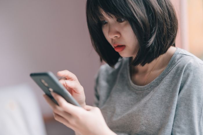 スマホでカードの明細を見て驚いている女性
