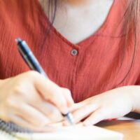 ノートに何か書いている女性