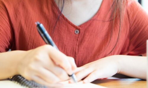 ノートに何か書いている女性