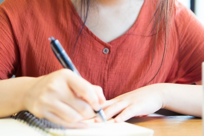 ノートに何か書いている女性